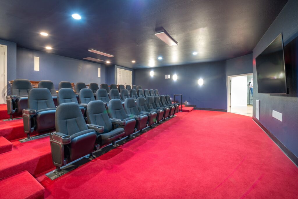 Media room with theater style seats and a large TV