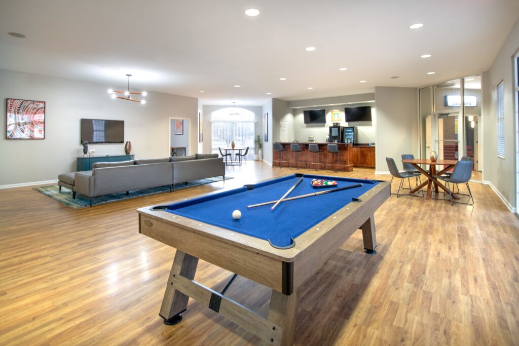 Clubhouse lounge with Billiards table and sofas around a TV, and a drink station